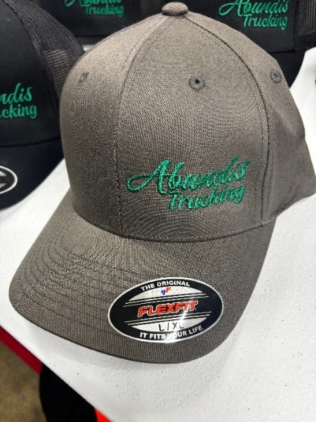 Gray baseball cap with green Alaskan trucking embroidered logo and NEXT brand label